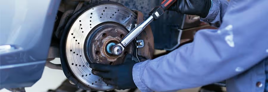 Mechanic tightening bolts on a car’s brake rotor during a brake inspection and repair service.