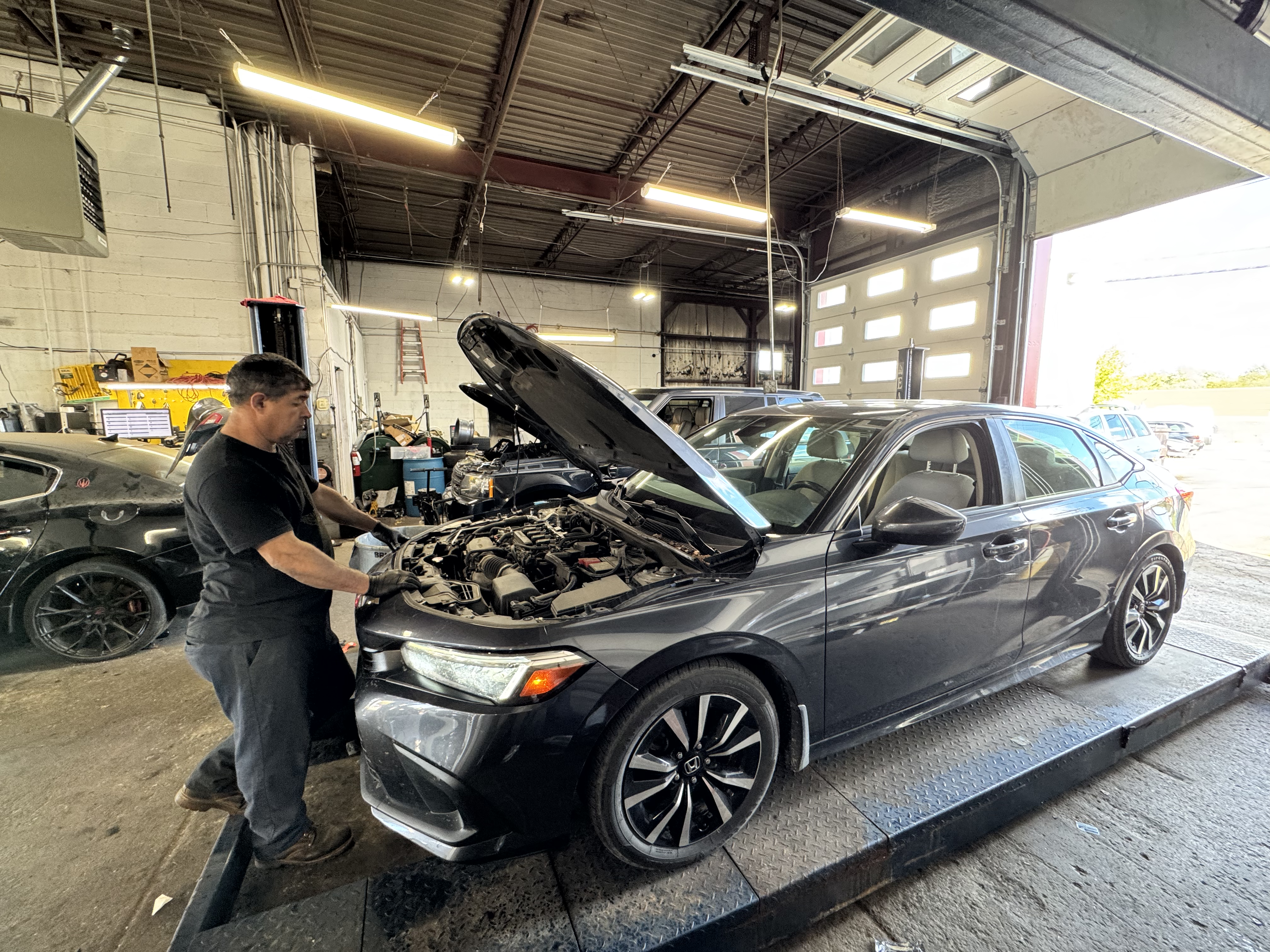 Mechanic performing engine diagnostics on a sedan inside Premier Tire & Autocare’s service bay.